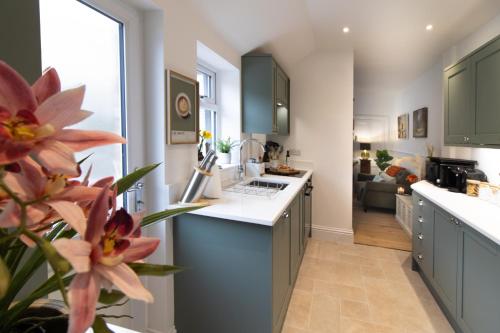 a kitchen with green cabinets and a flower in the foreground at Central Stamford Townhouse With Parking in Stamford