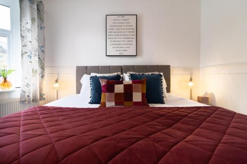 a bedroom with a large bed with a red comforter at Central Stamford Townhouse With Parking in Stamford
