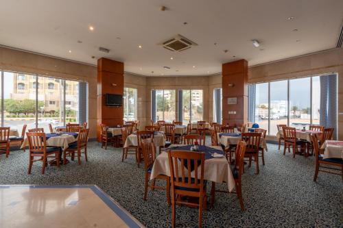 a dining room with tables and chairs and windows at Lavender Hotel Sharjah in Sharjah