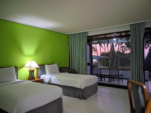a hotel room with two beds and a green wall at Grand Whiz Hotel Bromo in Bromo