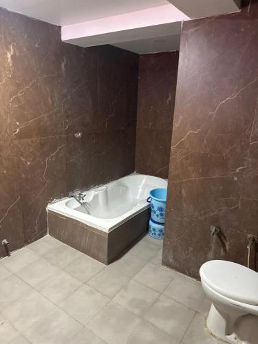 a bathroom with a bath tub and a toilet at hotel belva in Ahmedabad