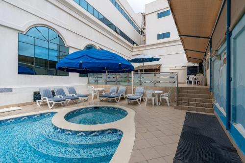 a pool with chairs and umbrellas next to a building at Lavender Hotel Sharjah in Sharjah