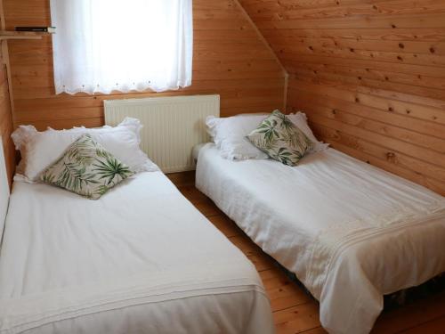 two beds in a room with wooden walls at Chata Sova Tále in Bystrá