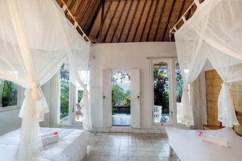a bedroom with white furniture and large windows at Taman Indrakila in Ubud