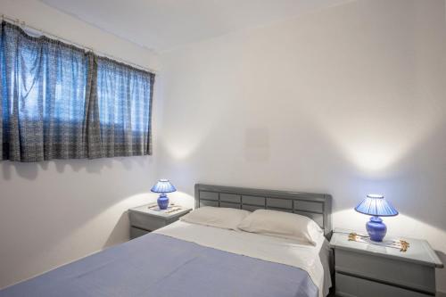 a white bedroom with two lamps on two tables at Onar holiday home in Fourka