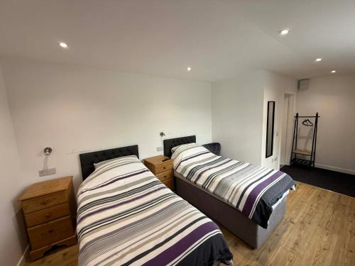 two beds in a room with white walls and wooden floors at The Carisbrooke in Forres