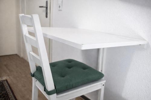 a white desk with a chair with a green seat at Kleine Wohnung für Singles in Daun