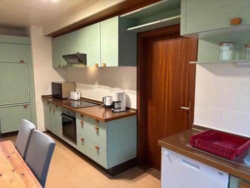 a kitchen with green and white cabinets and a table at Ferienwohnungen Falkenhagen in Dörpstedt