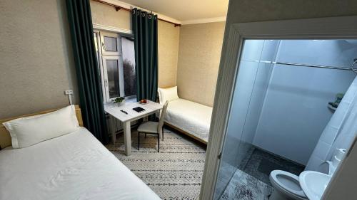 a hotel room with a bed and a desk and a window at Tabylga guest house in Jalal-Abad