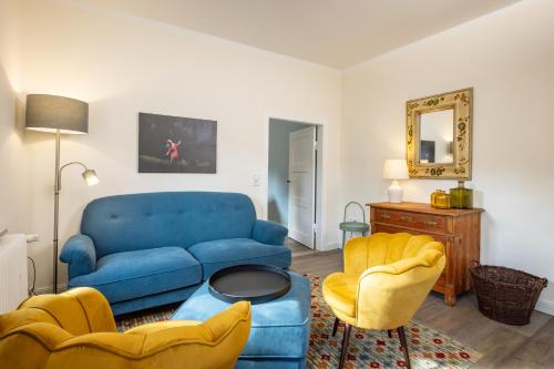 a living room with a blue couch and two chairs at Pförtnerhaus in Gartow