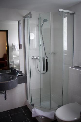 a bathroom with a glass shower and a sink at Hotel Restaurant Passmann in Lüdenscheid