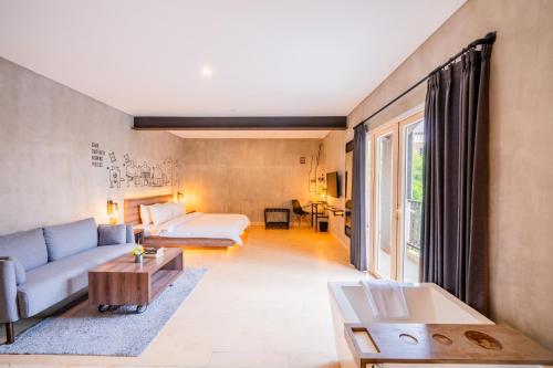 a living room with a couch and a bed at The All New Stark Boutique Hotel in Kuta