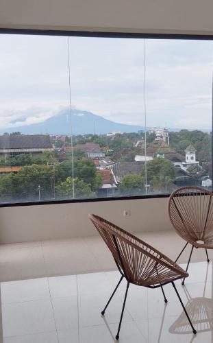 two chairs sitting in front of a large window at Grownicle Living Syariah in Yogyakarta