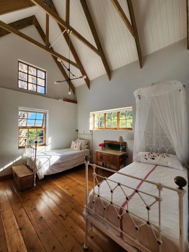 two beds in a room with wooden floors and windows at Pekárna in Vosburg