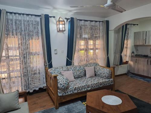 a living room with a couch and two windows at The Ocean Pearl in Diani Beach