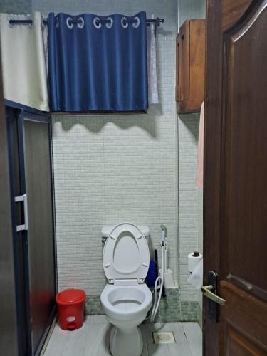 a bathroom with a toilet with a blue shower curtain at The Ocean Pearl in Diani Beach