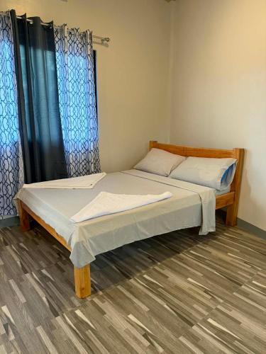 two beds in a room with blue curtains at New Apartment in Panglao Island