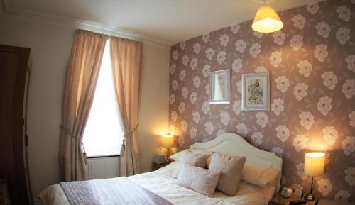 a bedroom with a bed and a flowery wallpaper at Lindisfarne House in Keswick