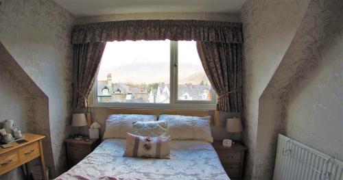 a bedroom with a bed and a large window at Lindisfarne House in Keswick