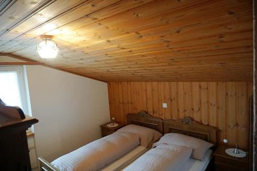 two beds in a room with a wooden ceiling at Hotel Tannenboden - Steinbock in Flumserberg