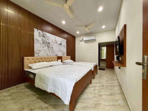 a bedroom with a large bed and a flat screen tv at Kanasu Residency Malpe in Udupi