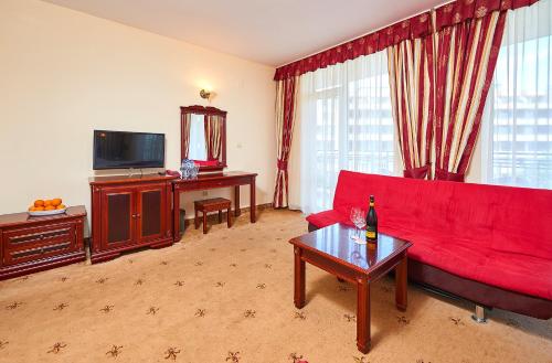 a living room with a red couch and a television at Karolina Hotel in Sunny Beach