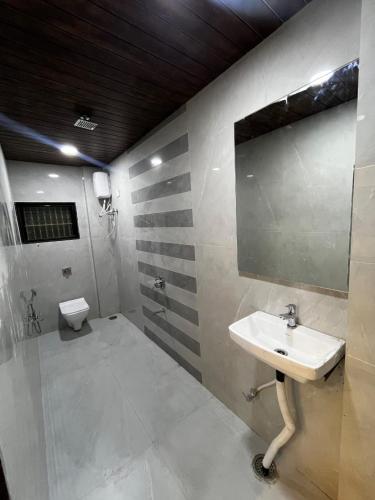a bathroom with a sink and a mirror and a toilet at Hotel Tulsi in Aurangabad