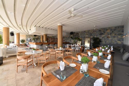 a restaurant with wooden tables and chairs and tablesearcher at Sirene Luxury Hotel Bodrum in Yalıkavak