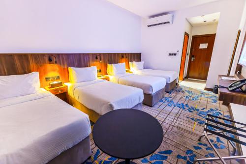 a hotel room with three beds and a table at Jasmine Garden Makkah in Al Masfalah