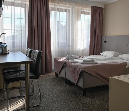 ein Schlafzimmer mit Bett, Schreibtisch und Fenstern in der Unterkunft Hotel Kolorowa in Karpacz