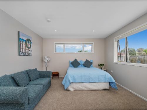 a bedroom with a bed and a couch at Soleil Studio - Whangamata Self-contained Unit in Whangamata