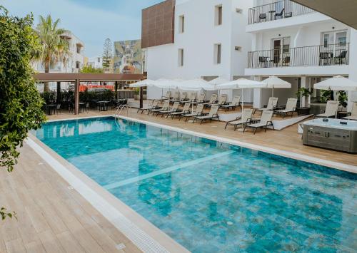 a swimming pool with chairs and a building at Cosmo Napa Boutique Hotel in Ayia Napa