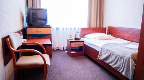 a bedroom with a bed and a tv and a chair at Zajazd Przy Granicy in Słuczanka