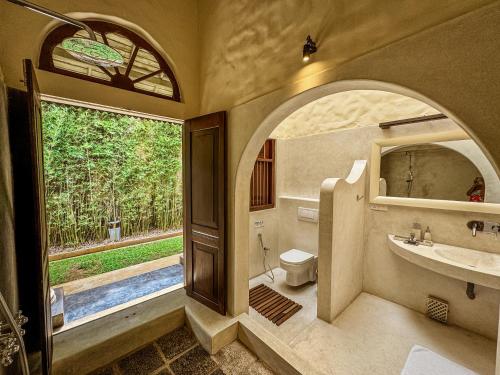 a bathroom with a sink and a toilet and a window at Heenatigala Walawwa - Free Shuttle to Our Private Beach in Talpe