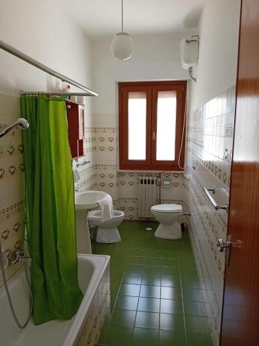 a bathroom with two toilets and a green shower curtain at La Casa di Rossella in Scanno