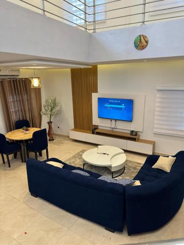 ein Wohnzimmer mit einer blauen Couch und einem Fernseher in der Unterkunft Opulence Résidence in Godomey