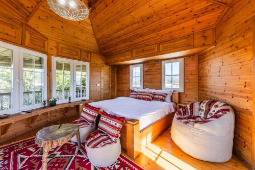 a bedroom with a bed and two chairs and windows at Ferma Gold by PikHost in Tirana