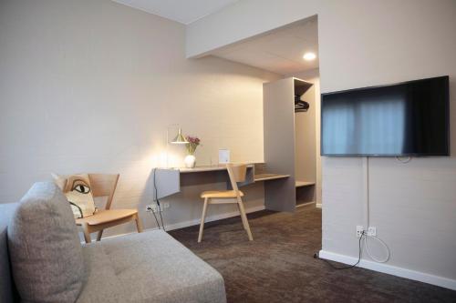 a living room with a couch and a desk and a tv at Fjelsted Skov Hotel & Konference in Ejby