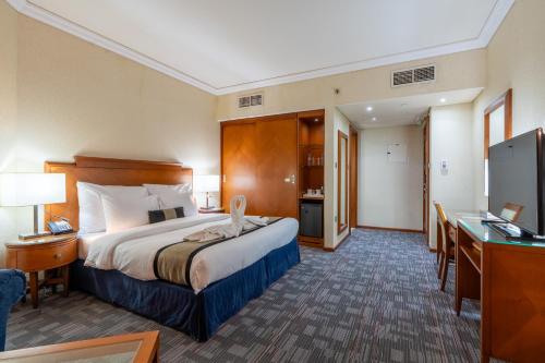 a hotel room with a bed and a desk at Lavender Hotel Sharjah in Sharjah