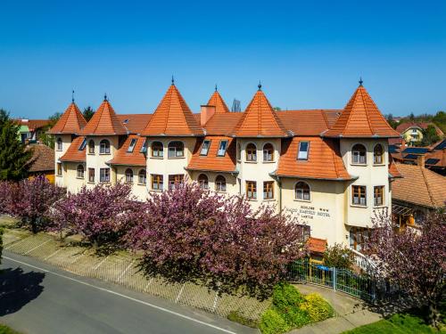 a large building with orange roofs on a street at Hajdú Kastély Hotel in Hajdúszoboszló