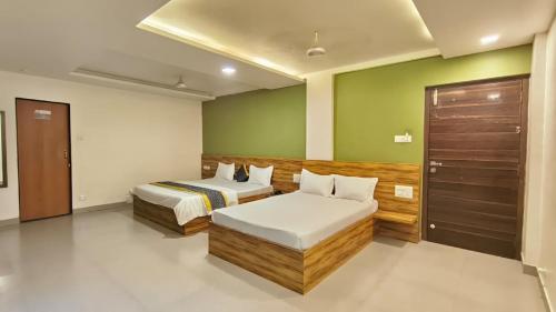 two beds in a room with green walls at Lotus Beach Resort in Nagaon