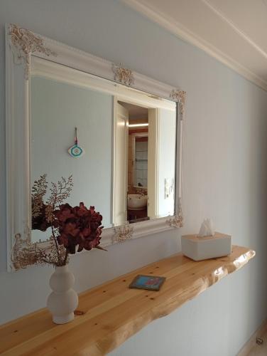 a mirror and a vase with flowers on a shelf at Vivi's Apartments Loft in Spetses