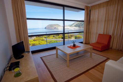 a living room with a table and a large window at Cantinho das Buganvilias AT**** in Queimada
