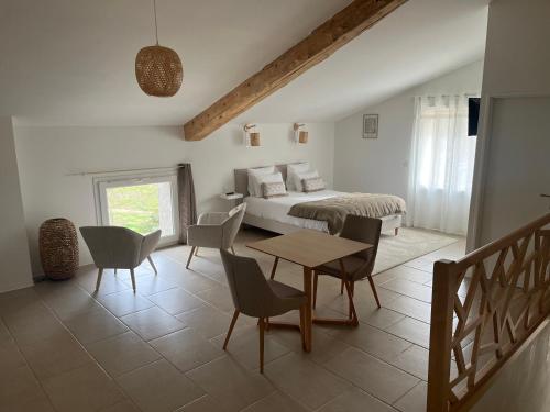 a bedroom with a bed and a table and chairs at LE MAS de PAUL in Saint-Julien-de-Cassagnas