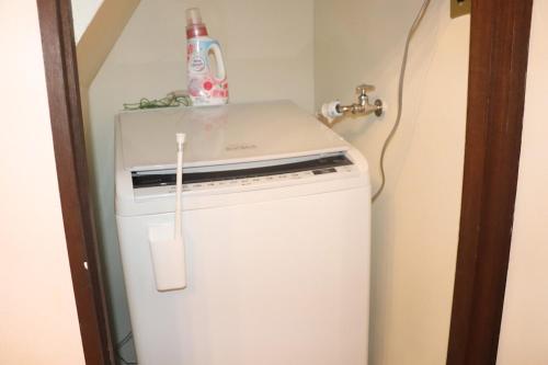 a small white refrigerator with a bottle on top of it at 名古屋駅 中部国際空港近くの宿ひろし in Nagoya