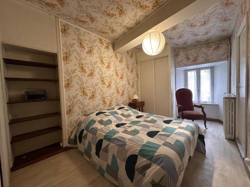 a bedroom with a bed and a chair at Murat - La maison de la petite place in Murat