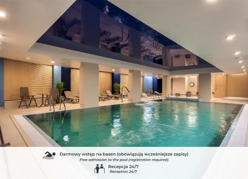 a large swimming pool in a hotel with tables and chairs at GRANO APARTMENTS Gdańsk Motława SPA & Wellness in Gdańsk