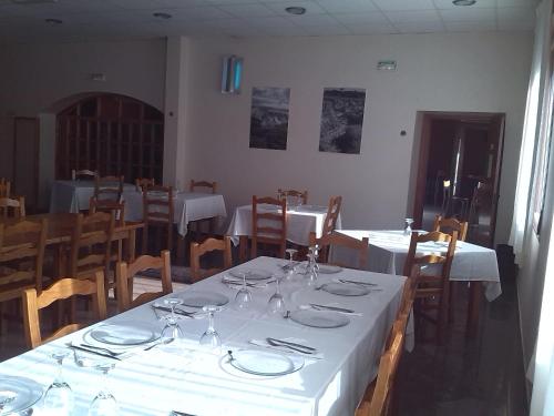a dining room with white tables and wooden chairs at Camino de las Bardenas in Arguedas