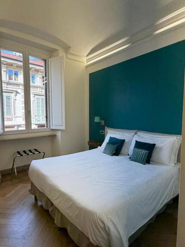 a bedroom with a large white bed with a blue wall at XX SETTEMBRE Urban Relais in Turin
