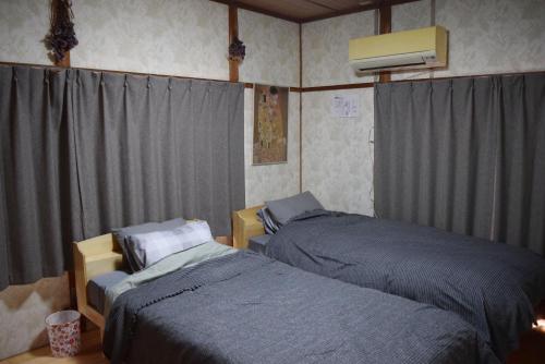 a bedroom with two beds and a air conditioner at やぎみちの家 yagimichi-noie in Sasebo